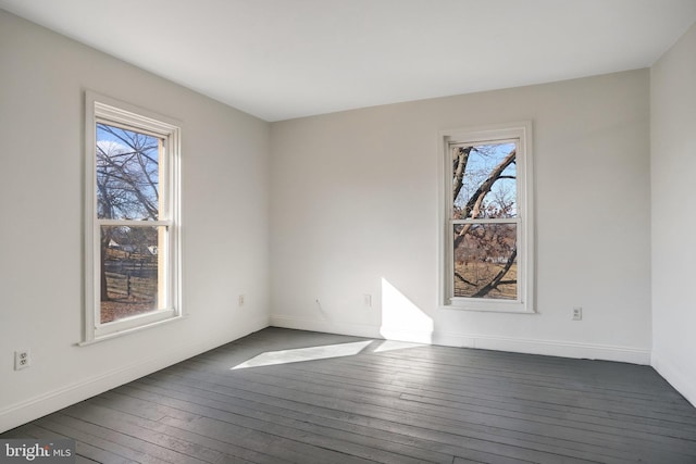 spare room featuring a healthy amount of sunlight, dark wood-style floors, and baseboards