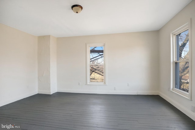 spare room with a wealth of natural light, baseboards, and dark wood-style flooring