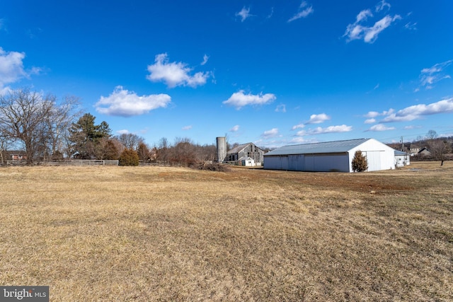 view of yard with an outbuilding, a rural view, an outdoor structure, and fence