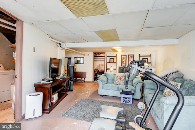 living room with a paneled ceiling, concrete flooring, and washer / dryer