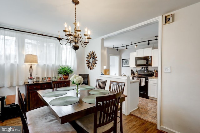 dining area with light hardwood / wood-style flooring, rail lighting, and a chandelier