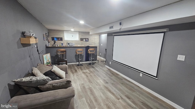 cinema room with light wood-type flooring and bar