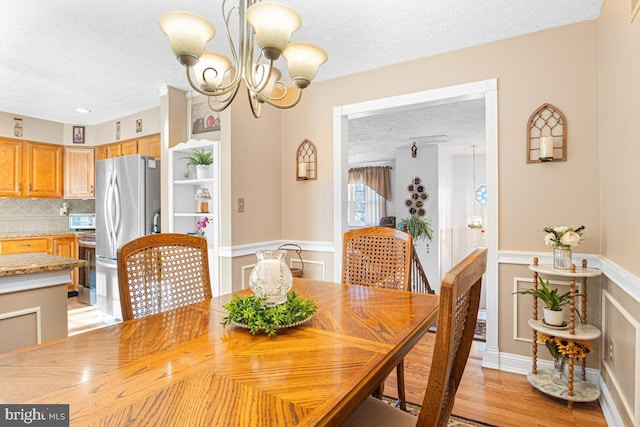 dining room featuring a notable chandelier, light hardwood / wood-style flooring, and a textured ceiling