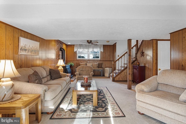 living room featuring ceiling fan, light colored carpet, and wooden walls