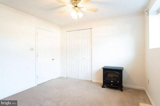 unfurnished bedroom with crown molding, light colored carpet, a closet, and a wood stove