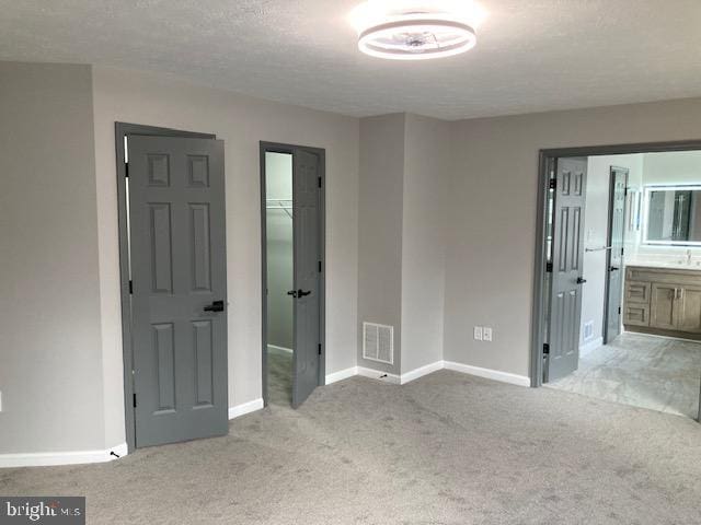 unfurnished bedroom with light colored carpet, visible vents, a spacious closet, and baseboards