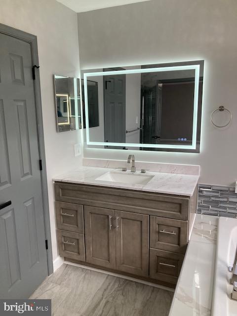 bathroom featuring marble finish floor, a bath, and vanity