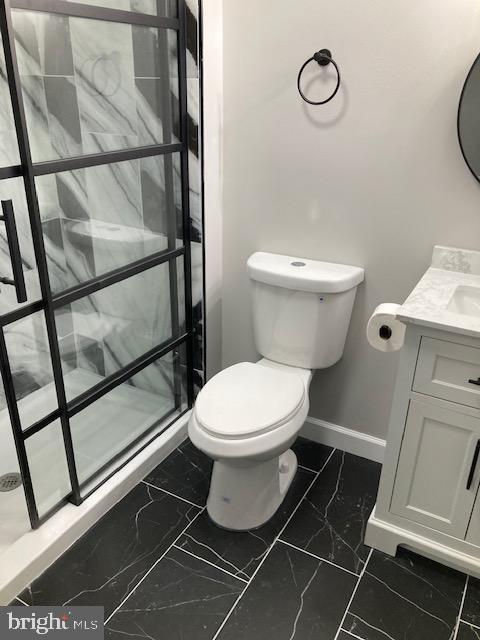 full bath featuring marble finish floor, toilet, vanity, a walk in shower, and baseboards