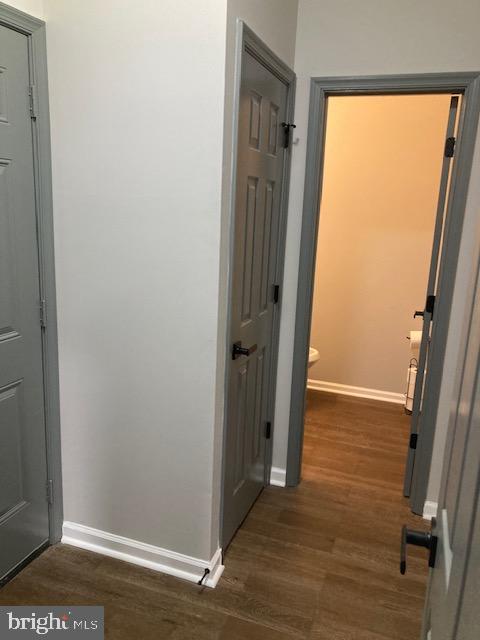 hall with dark wood-type flooring and baseboards