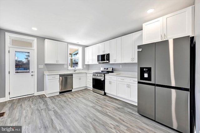 kitchen featuring sink, stainless steel appliances, white cabinets, and light wood-type flooring