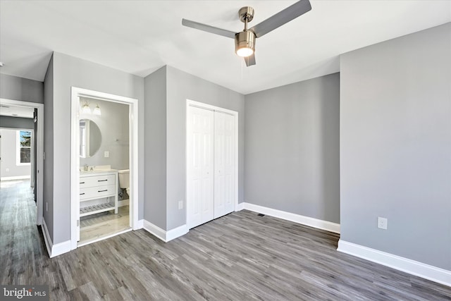 unfurnished bedroom featuring connected bathroom, sink, dark hardwood / wood-style flooring, a closet, and ceiling fan