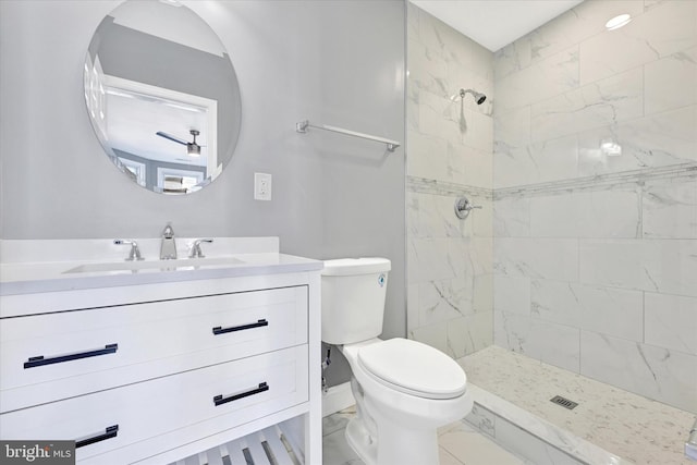 bathroom featuring vanity, a tile shower, and toilet