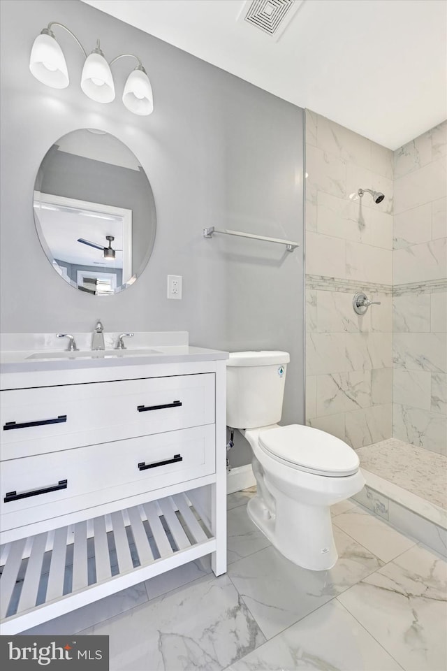 bathroom with vanity, toilet, and a tile shower