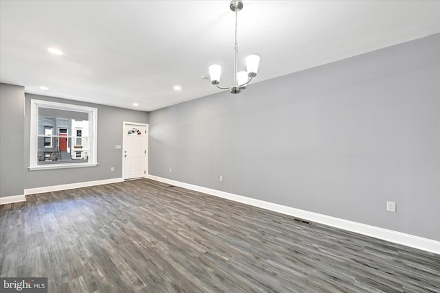 empty room featuring an inviting chandelier and dark wood-type flooring