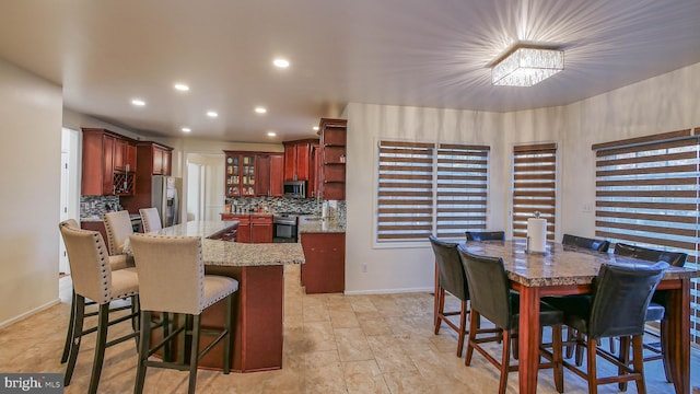 kitchen with tasteful backsplash, light stone countertops, appliances with stainless steel finishes, and a breakfast bar