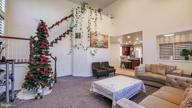 carpeted living room featuring a towering ceiling and a wealth of natural light