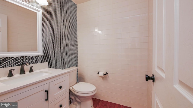 bathroom with wood-type flooring, tile walls, vanity, and toilet