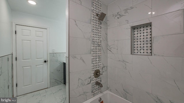 bathroom with tile walls and tiled shower / bath