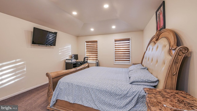 bedroom featuring a raised ceiling and dark colored carpet