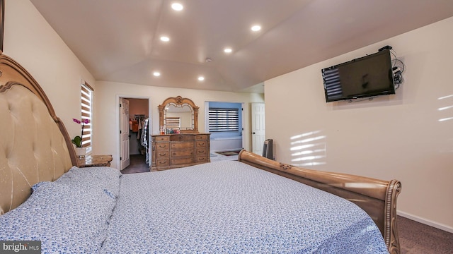 bedroom featuring lofted ceiling, dark carpet, and a spacious closet