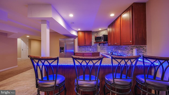 bar with tasteful backsplash, light colored carpet, appliances with stainless steel finishes, and light stone countertops