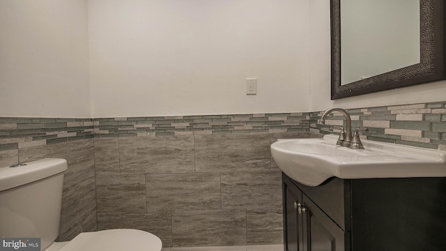 bathroom with vanity, tile walls, and toilet