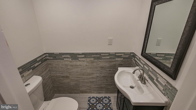 bathroom featuring vanity, tile walls, and toilet