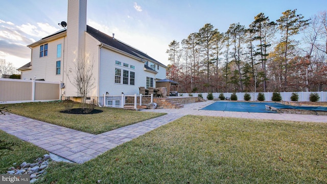 rear view of house featuring a yard, a covered pool, and a patio area