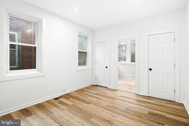 unfurnished bedroom featuring two closets and light hardwood / wood-style flooring