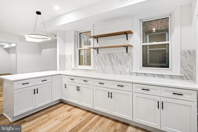 kitchen with white cabinetry, hanging light fixtures, tasteful backsplash, and light wood-type flooring