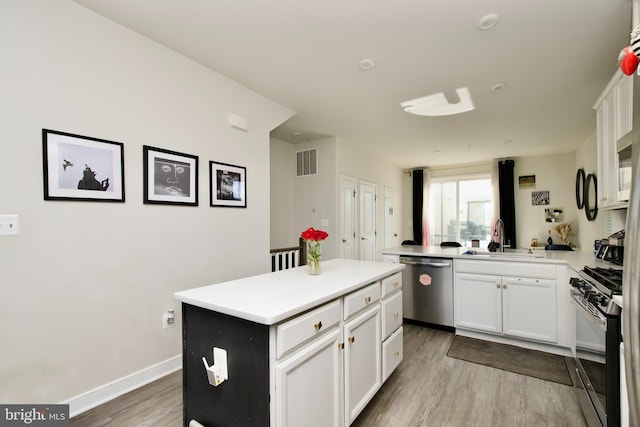 kitchen with appliances with stainless steel finishes, white cabinetry, sink, a center island, and kitchen peninsula