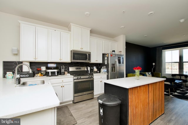 kitchen with tasteful backsplash, white cabinetry, sink, a center island, and stainless steel appliances