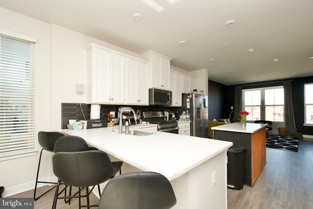 kitchen featuring white cabinetry, a center island, kitchen peninsula, stainless steel appliances, and decorative backsplash