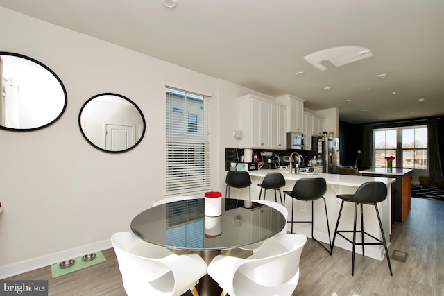 dining space with sink and light hardwood / wood-style floors