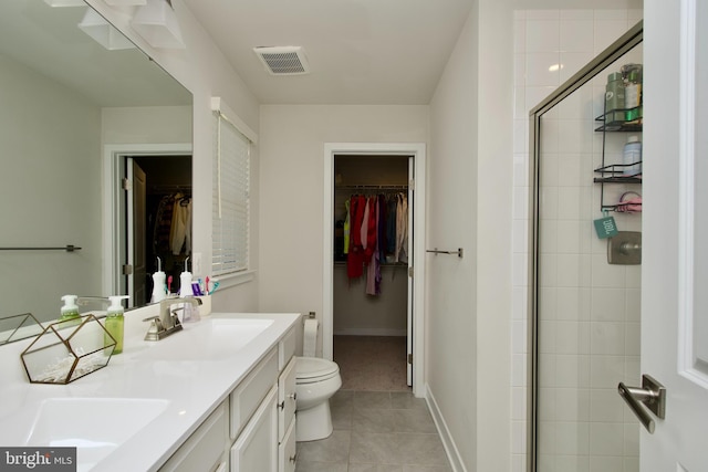 bathroom with a shower with door, vanity, tile patterned floors, and toilet