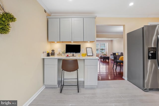 kitchen with stainless steel fridge, baseboards, ornamental molding, wood tiled floor, and light countertops