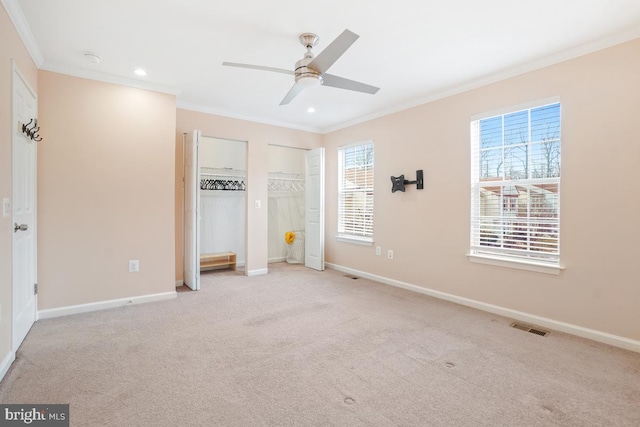 unfurnished bedroom with baseboards, visible vents, multiple closets, and ornamental molding