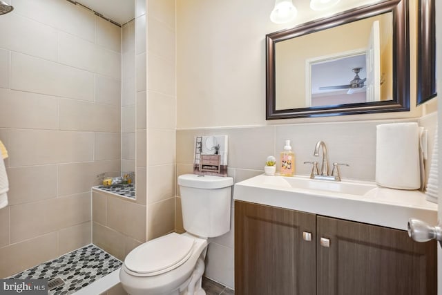 full bathroom with toilet, a ceiling fan, vanity, and tile walls