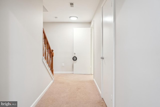 hallway with light carpet, stairs, and baseboards