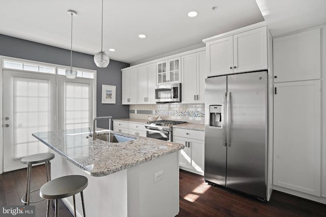 kitchen with sink, white cabinetry, an island with sink, stainless steel appliances, and light stone countertops