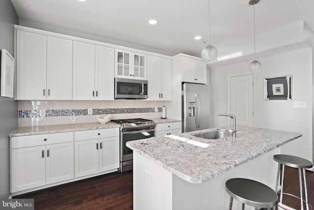 kitchen featuring decorative light fixtures, sink, white cabinets, a kitchen island with sink, and stainless steel appliances