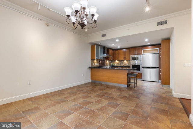 kitchen featuring crown molding, appliances with stainless steel finishes, backsplash, and wall chimney exhaust hood