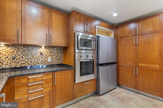 kitchen with tasteful backsplash, appliances with stainless steel finishes, and dark stone countertops