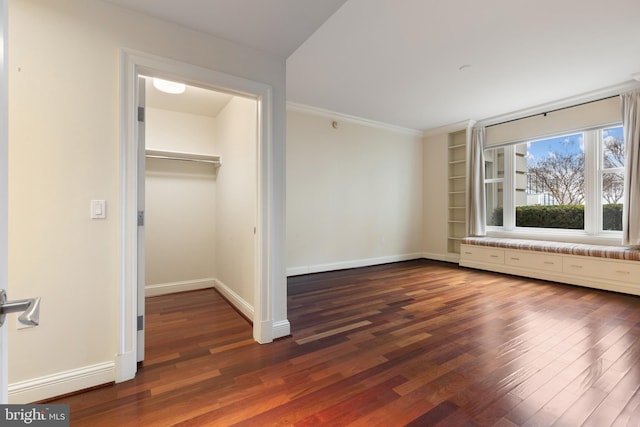 unfurnished bedroom featuring a walk in closet, dark wood-type flooring, and a closet