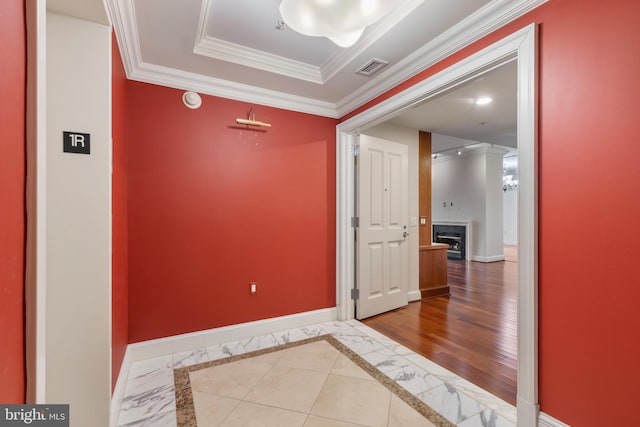 corridor with crown molding, a raised ceiling, and hardwood / wood-style flooring