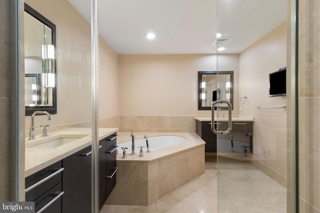 bathroom with tiled tub, vanity, and tile patterned floors