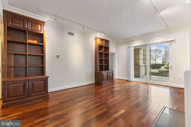 unfurnished living room featuring crown molding, dark wood-type flooring, and track lighting