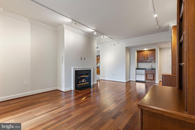 unfurnished living room featuring ornamental molding, rail lighting, sink, and dark hardwood / wood-style flooring