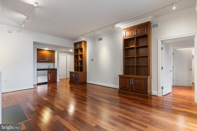 unfurnished living room with sink, dark wood-type flooring, ornamental molding, and rail lighting