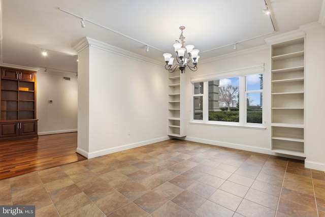 unfurnished dining area featuring an inviting chandelier, ornamental molding, and rail lighting